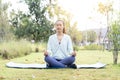 Asian woman doing lotus yoga position outside in the garden