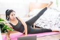 Asian woman doing sport indoors, female doing yoga at home watching video from laptop Royalty Free Stock Photo
