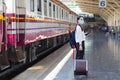 Asian woman drag her bag to travel or come back to home by train at station while she wears medical face mask. Royalty Free Stock Photo