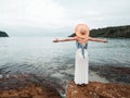 Asian woman in dress and straw hat looking away to the turquoise calm sea water. female open arms on the rock at tropical beach in Royalty Free Stock Photo