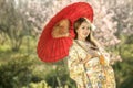 Asian woman with dress traditional Chameleon and red umbrella. Royalty Free Stock Photo