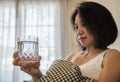 Asian woman drink water after wake up in the morning sitting on a bed Royalty Free Stock Photo