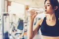 Asian woman drinking pure drinking water for freshness after workout or exercise training in fitness gym with fitness equipment b Royalty Free Stock Photo