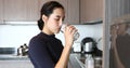 Asian woman drinking water on glass in kitchen Royalty Free Stock Photo