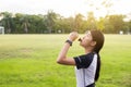 Asian woman drinking water after running exercise at the garden in sunset Royalty Free Stock Photo