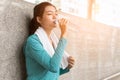 Asian woman drinking water to rehydrate to avoid heat stroke after running outdoors in the summer