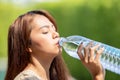 Asian Woman drinks big bottle water in outdoor green bokeh tree background Royalty Free Stock Photo