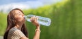 Asian Woman drinks big bottle water in outdoor green bokeh tree background Royalty Free Stock Photo
