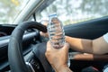 Asian woman driver holding bottle for drink water while driving a car. Royalty Free Stock Photo