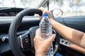 Asian woman driver holding bottle for drink water while driving a car. Plastic hot water bottle cause fire Royalty Free Stock Photo