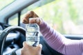 Asian woman driver holding bottle for drink water while driving a car. Plastic hot water bottle cause fire Royalty Free Stock Photo