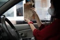 Woman in protective mask driving a car on road. Safe traveling. Royalty Free Stock Photo