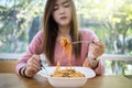 Asian woman eating instant noodles with fork on blurred background of restaurant Royalty Free Stock Photo