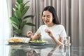 Asian woman eating vegetable salad mix with tomato for healthy meal on the table in dining room at home Royalty Free Stock Photo