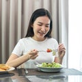 Asian woman eating vegetable salad mix with tomato for healthy meal on the table in dining room at home Royalty Free Stock Photo