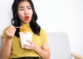 Asian woman eating very hot and spicy noodle from a cup her mouth and tongue burning and red