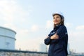 Asian woman engineer arm crossed and smile with confident looking forward to future with oil refinery plant factory in background Royalty Free Stock Photo