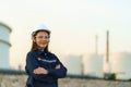 Asian woman engineer arm crossed and smile with confident looking forward to future with oil refinery plant factory in background Royalty Free Stock Photo