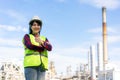 Asian woman engineer arm crossed and thumb up with confident looking forward to future with oil refinery plant factory in