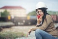 Asian woman engineer or construction worker wearing safety hat helmet and holding portable radio at railway project. Civil