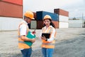 asian wman Engineer with note clipboard and asian man Supervisor in Hard Hats and Safety Vests Stand in Container Terminal. Royalty Free Stock Photo