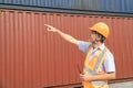 asian wman Engineer with note clipboard and asian man Supervisor in Hard Hats and Safety Vests Stand in Container Terminal. Royalty Free Stock Photo