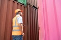 asian wman Engineer with note clipboard and asian man Supervisor in Hard Hats and Safety Vests Stand in Container Terminal. Royalty Free Stock Photo