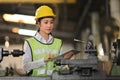 Asian woman engineering manager in safety hard hat and reflective cloth is inspecting inside the lathe factory