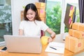 Asian woman enjoy herself while using internet on laptop and phone in office. Business and marketing and part time concept.