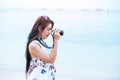 Asian woman enjoy take photo by digital camera at beach. Single Royalty Free Stock Photo