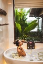 Asian woman enjoying in flower spa bath with foam, bubbles and yellow flowers Royalty Free Stock Photo