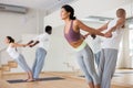 Asian woman exercising assisted yoga poses in pair in yoga studio