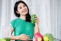 Asian woman experiencing delight and vitality relishes a refreshing blend of green fruits and vegetable juice