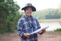 Asian woman explorer hold paper map to explore nature at forest and lake area.