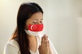 Asian woman in face mask praying for Singapore