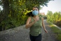 Asian woman in face mask running workout during covid-19 deconfinement- young dedicated Korean girl jogging at beautiful city park Royalty Free Stock Photo