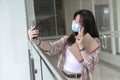 Woman with face mask taking self portrait with her cellphone