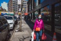 Asian woman with face mask walking down street in Flushing Chinatown