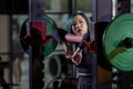 Asian woman is facing overtraining syndrome on practice weight lifting using barbell for arm and core muscle inside gym with dark