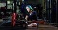 Asian woman is facing overtraining syndrome after weight training workout inside gym with dark background for exercising