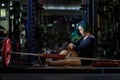 Asian woman is facing overtraining syndrome after weight training workout inside gym with dark background for exercising and