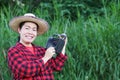 Asian woman farmer, holds AM, FM transistor radio receiver on shoulder.