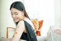 Asian woman feeling happily in love and sitting on sofa with heart stickers on her arms Royalty Free Stock Photo