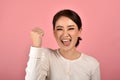 Asian woman feeling happy and excited on accomplish success on pink background.