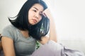 Asian woman feeling sad and depressed sitting in bed next to the window