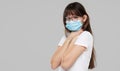 Asian woman feeling unwell and wearing face protective mask on grey studio background. Royalty Free Stock Photo