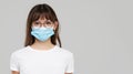 Asian woman feeling unwell and wearing face protective mask on grey studio background. Royalty Free Stock Photo