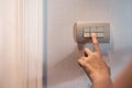 Asian woman finger is turning off on grey light switch over textile texture wall in the hotel. Copy space. Royalty Free Stock Photo
