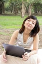 Asian woman flagging with laptop sitting at park Royalty Free Stock Photo