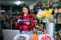 Asian Woman Florist Small Business Flower Shop Owner and She is using her telephone and laptop to take orders for her store Royalty Free Stock Photo